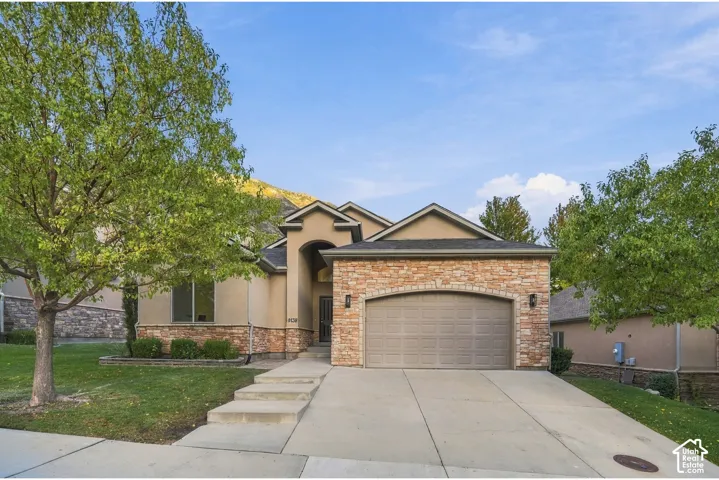 Stucco exterior with stone accents, a two-car garage, and a concrete driveway