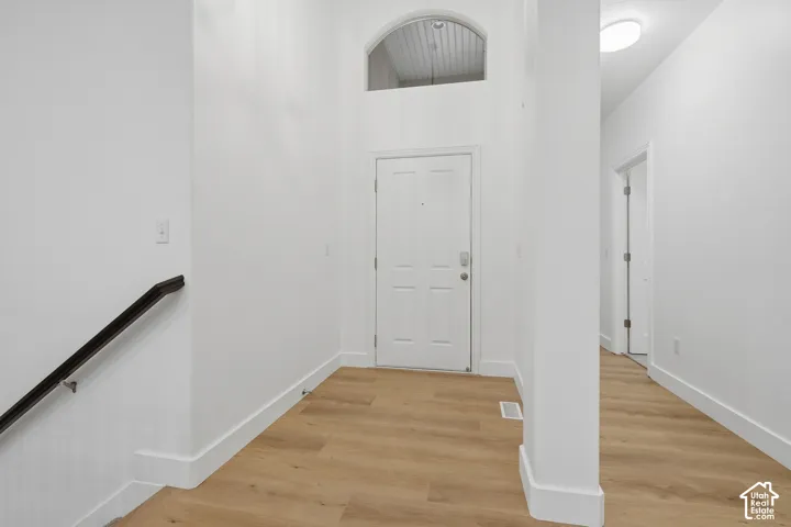 Entryway with wood-finish LVP flooring, white paneled door, and arched transom window