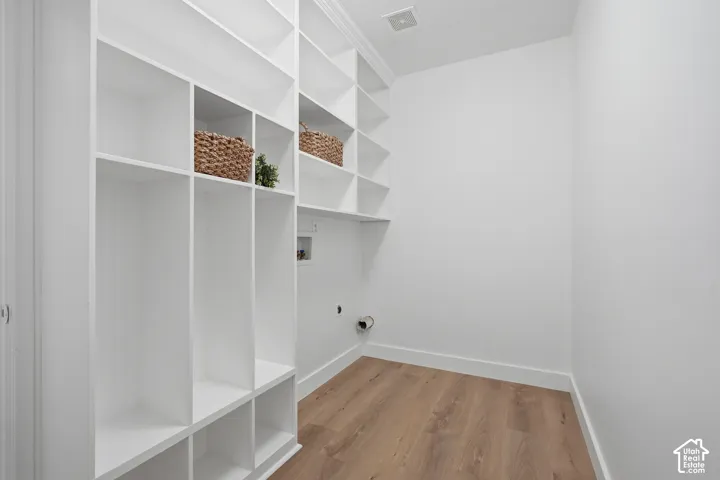 Laundry/mudroom with built-in shelving, wood-finish LVP flooring, white walls, and dedicated laundry hookups. Access to the garage.