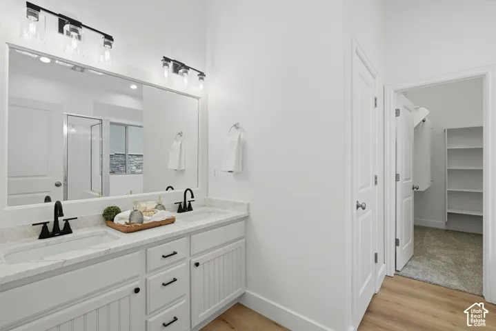 Primary bath with dual vanity with quartz countertop, matte black fixtures, toilet room and walk in closet