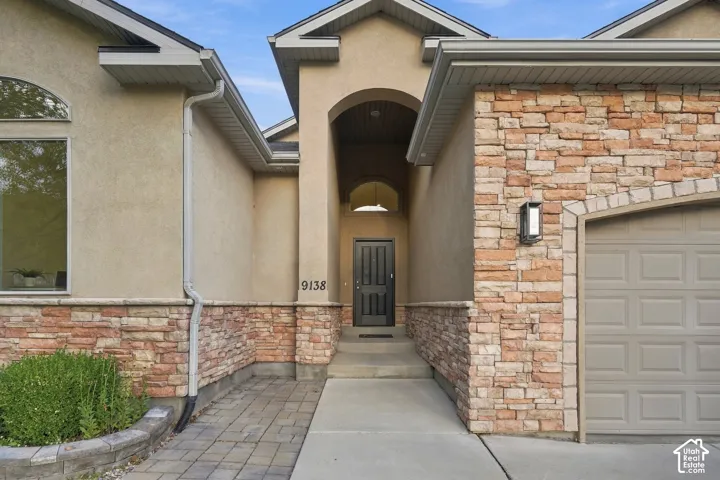 Stucco and stone home with an arched entry and covered porch