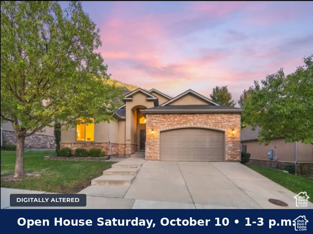 Stucco and stone facade with an arched entry, mature front landscaping, concrete driveway, and attached garage with an arched door