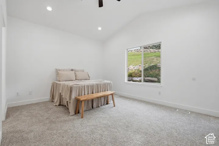Primary bedroom with vaulted ceiling, recessed lighting, carpet flooring, large window, and ceiling fan