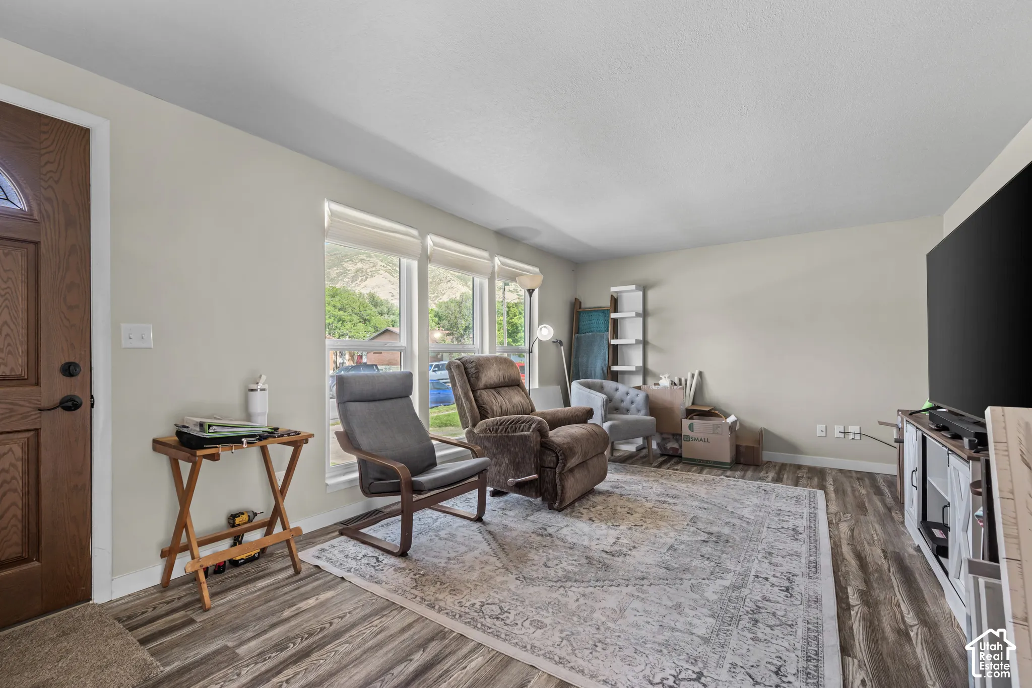 Wood-finish flooring throughout, light-toned wall paint, white trim, and a decorative paneled entry door