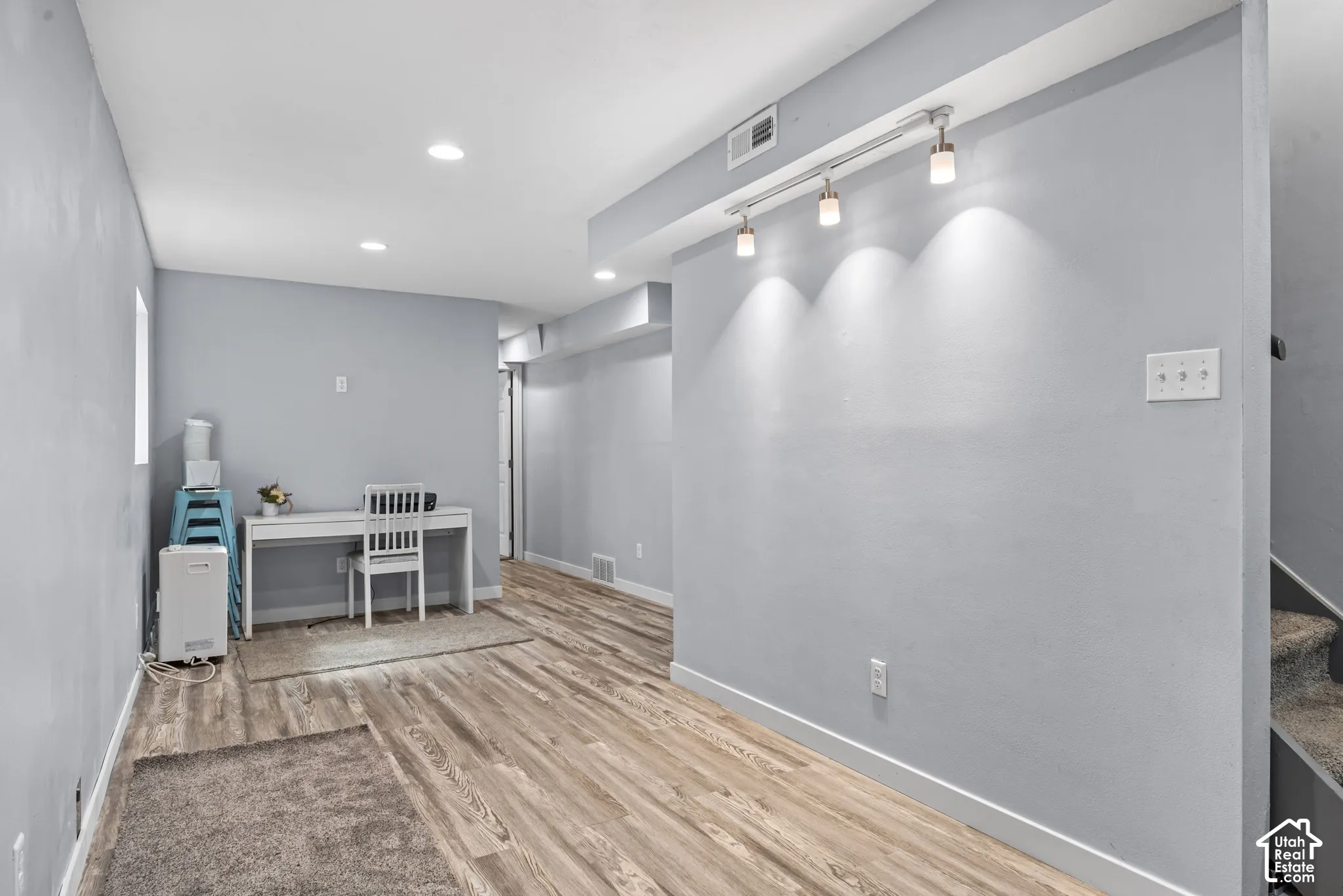 Recessed ceiling lighting, wood-finish flooring, painted walls, track lighting with three fixtures, and a window