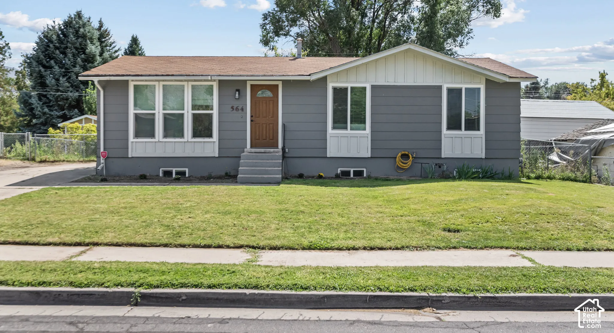 Gray siding exterior with white trim, brown entry door, concrete steps, and a grassy lawn