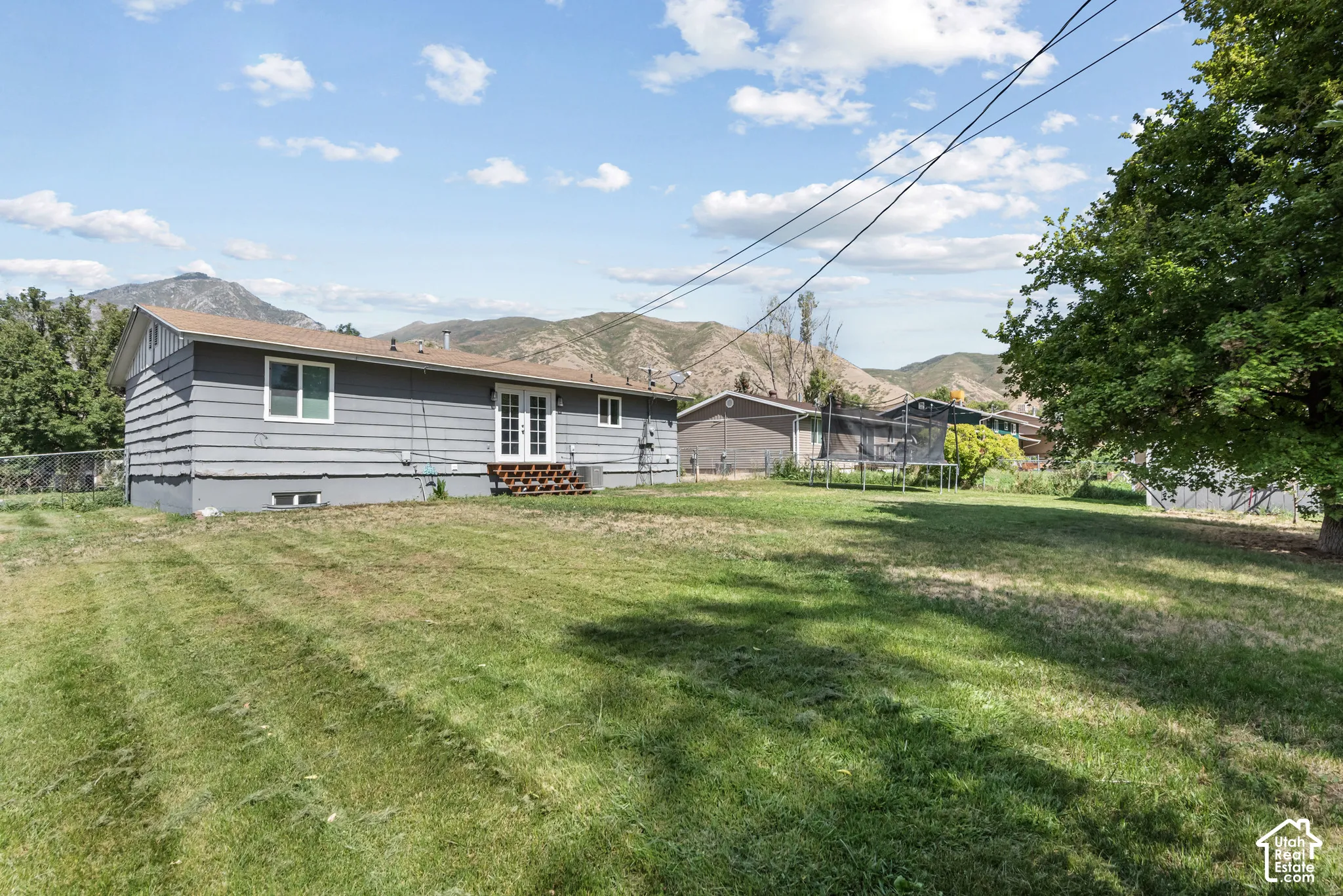 Expansive grassy yard with mature tree and mountain backdrop