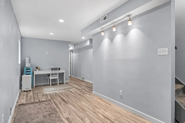Recessed ceiling lighting, wood-finish flooring, painted walls, track lighting with three fixtures, and a window