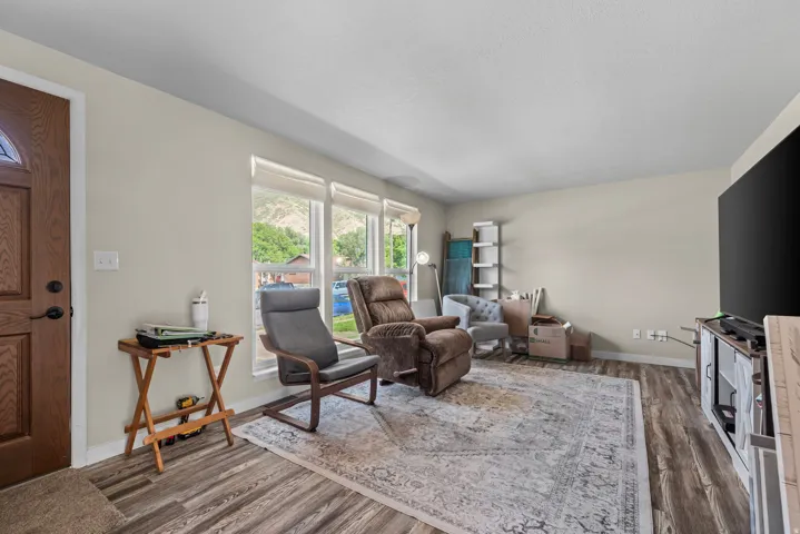 Wood-finish flooring throughout, light-toned wall paint, white trim, and a decorative paneled entry door