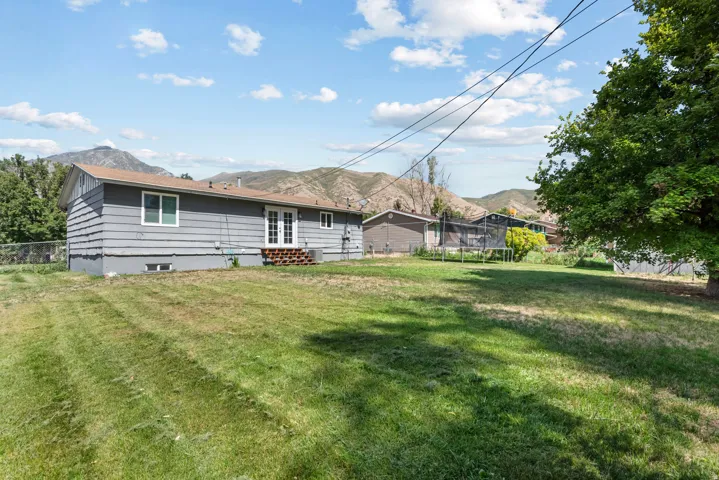 Expansive grassy yard with mature tree and mountain backdrop