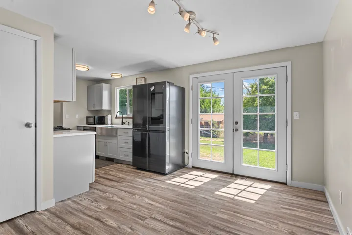 Wood-finish flooring throughout, with a kitchen featuring light cabinetry, a stainless steel farmhouse sink, and a black appliance package