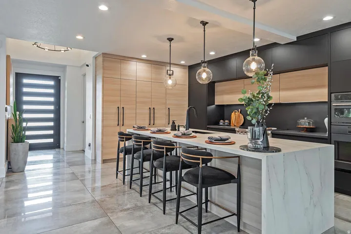 Modern kitchen featuring a waterfall island with integrated seating, pendant lighting, and built-in appliances