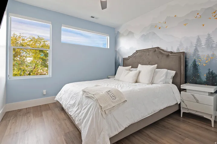 Wood-finish flooring, a decorative wall mural, and multiple windows
