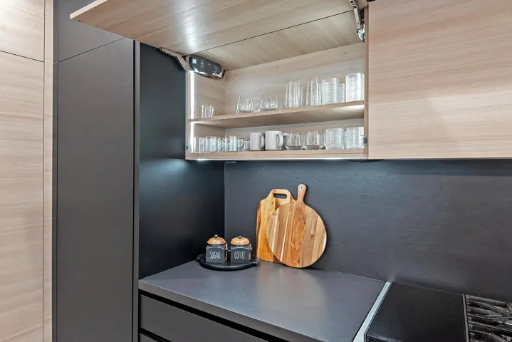 Integrated upper cabinetry with concealed hinges, under-cabinet lighting, and a dark stone-finish countertop