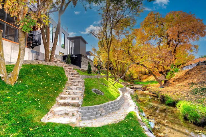Manicured lawn with a stone pathway, a retaining wall, a spiral staircase, and a serene water feature