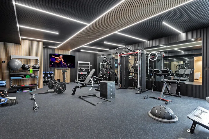 Dedicated fitness space featuring rubber flooring, integrated ceiling lighting, and a full-wall mirror