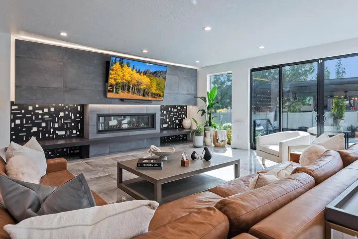 Recessed lighting illuminates a stone-clad fireplace wall with an integrated linear firebox