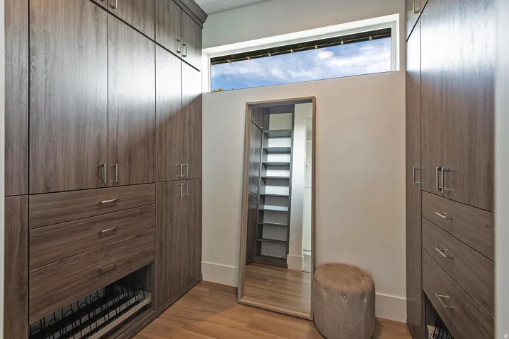 Built-in wood-finish cabinetry, integrated drawers, full-length mirror, high transom window, and wood-finish flooring