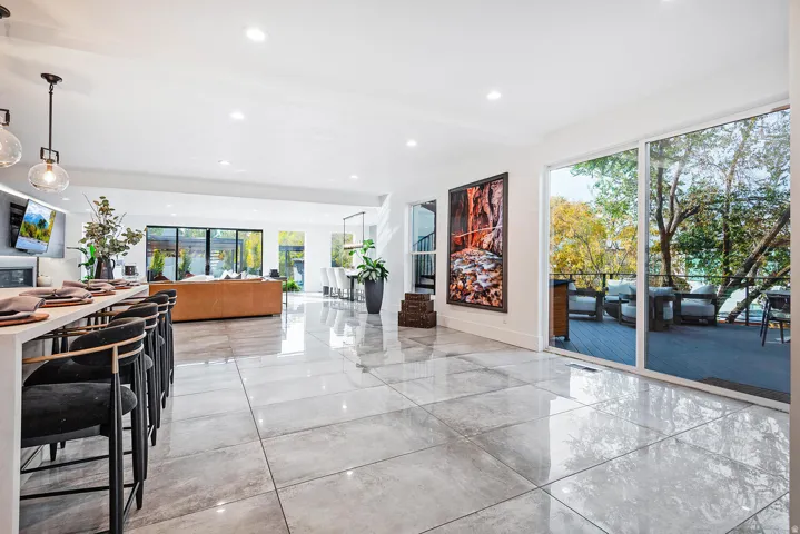 Polished tile flooring, recessed ceiling lighting, a built-in breakfast bar, and a sliding glass door opening to an exterior deck