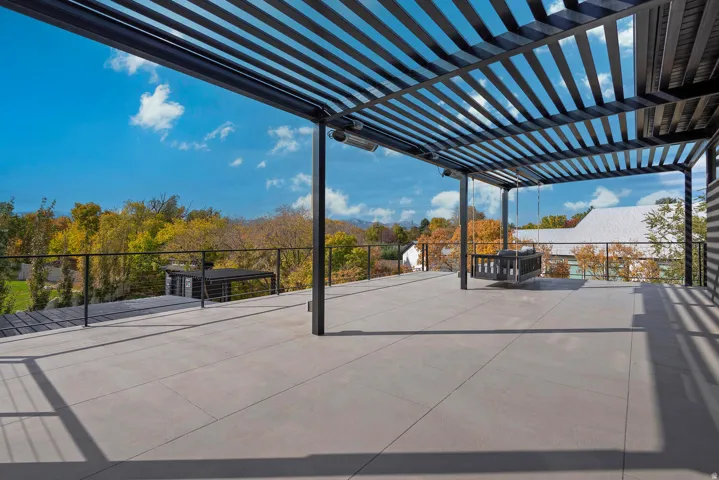 Expansive rooftop deck featuring a louvered pergola, durable tile flooring, and sleek metal railings