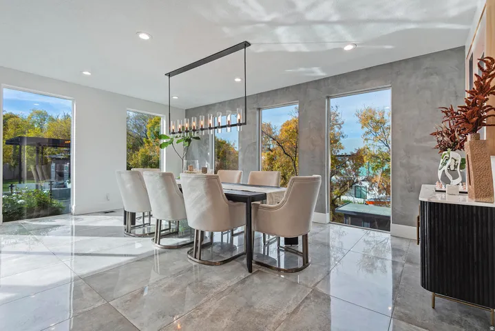 Recessed lighting, large format tile flooring, full-height windows, a linear chandelier, and a textured accent wall
