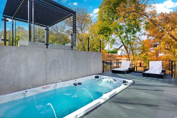 Swim spa with water features, composite decking, and black metal railings with glass panels