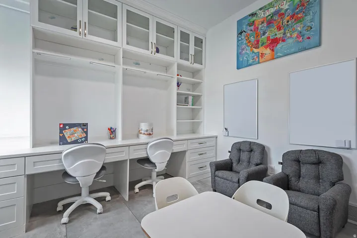 Built-in desk area featuring multiple workstations, integrated shelving, and upper cabinetry with glass-front doors