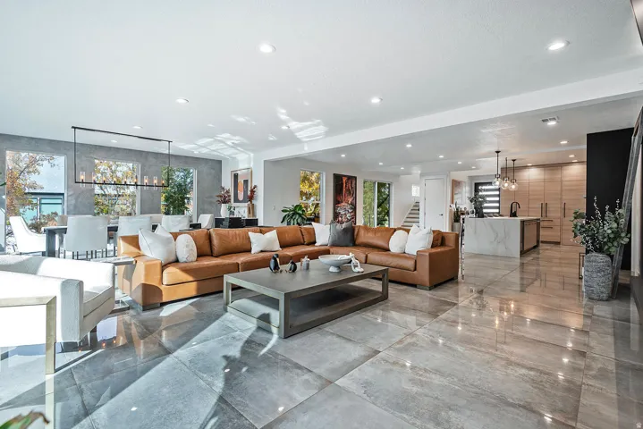 Spacious open-concept living area featuring large format tile flooring, recessed lighting, and a modern kitchen island with a waterfall countertop