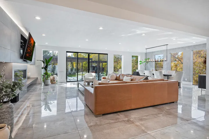 Open-concept living space featuring high-gloss tile flooring, a linear fireplace with a built-in hearth, and floor-to-ceiling sliding glass doors