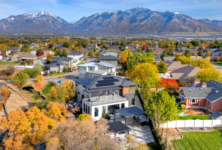 Modern residence with a multi-level roofline, solar panel installation, and a spacious upper-level balcony