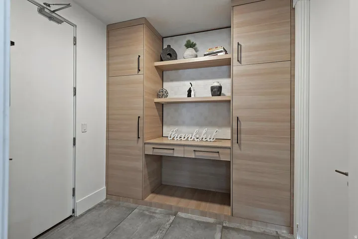 Integrated wood-finish cabinetry with black hardware, built-in desk, and open shelving