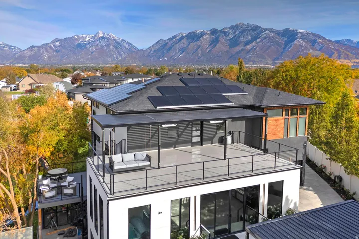 Multi-level residence featuring a large upper balcony, a lower deck, and a roofline with solar panels