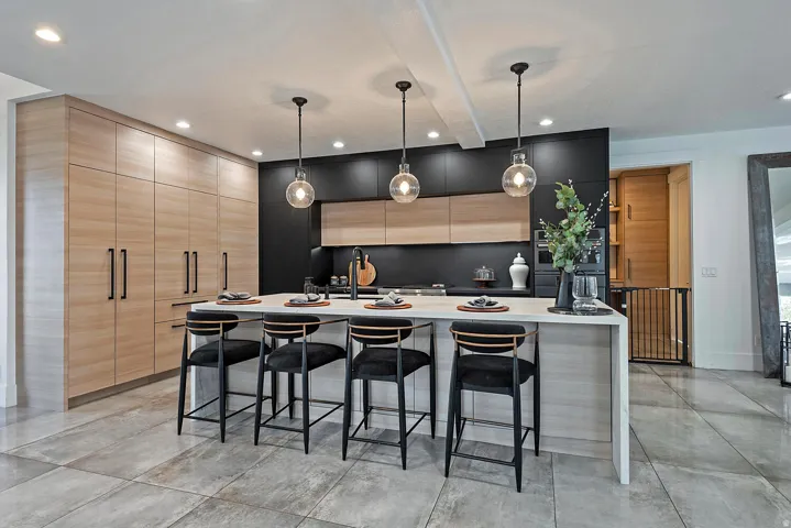Modern kitchen featuring extensive wood-finish cabinetry, a large center island with a light-toned countertop, and dark accent cabinetry