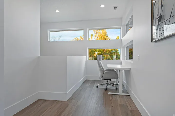 Recessed lighting, wood-finish flooring, multiple transom windows, built-in desk, and white walls