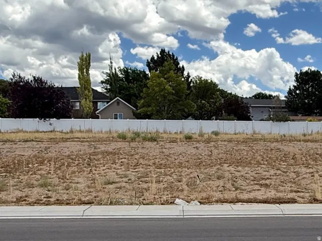 Level lot with a paved street frontage, defined by a white fence