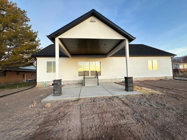 Expansive concrete patio with covered area, supported by stone-finish pillars