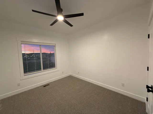 Recessed window featuring blinds, textured carpet flooring, and a ceiling fan with integrated lighting