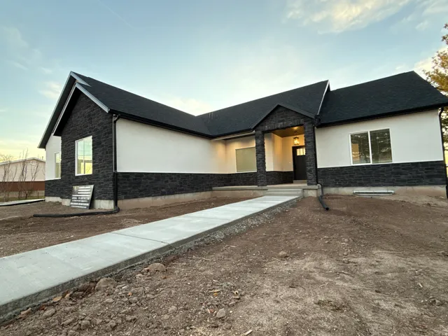 Contemporary exterior featuring a stone and stucco facade, a covered entry with columns, and an asphalt shingle roof