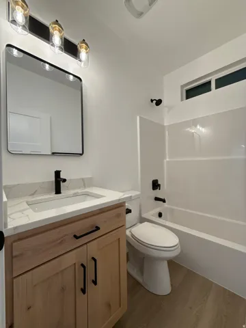 Vanity with wood-finish cabinetry, white countertop, and black fixtures