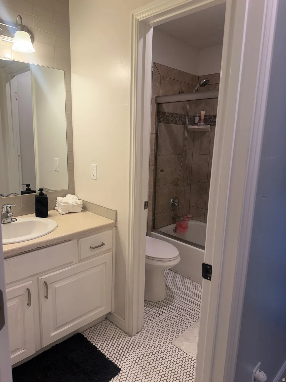 White vanity with a built-in sink, neutral countertop, and brushed nickel hardware