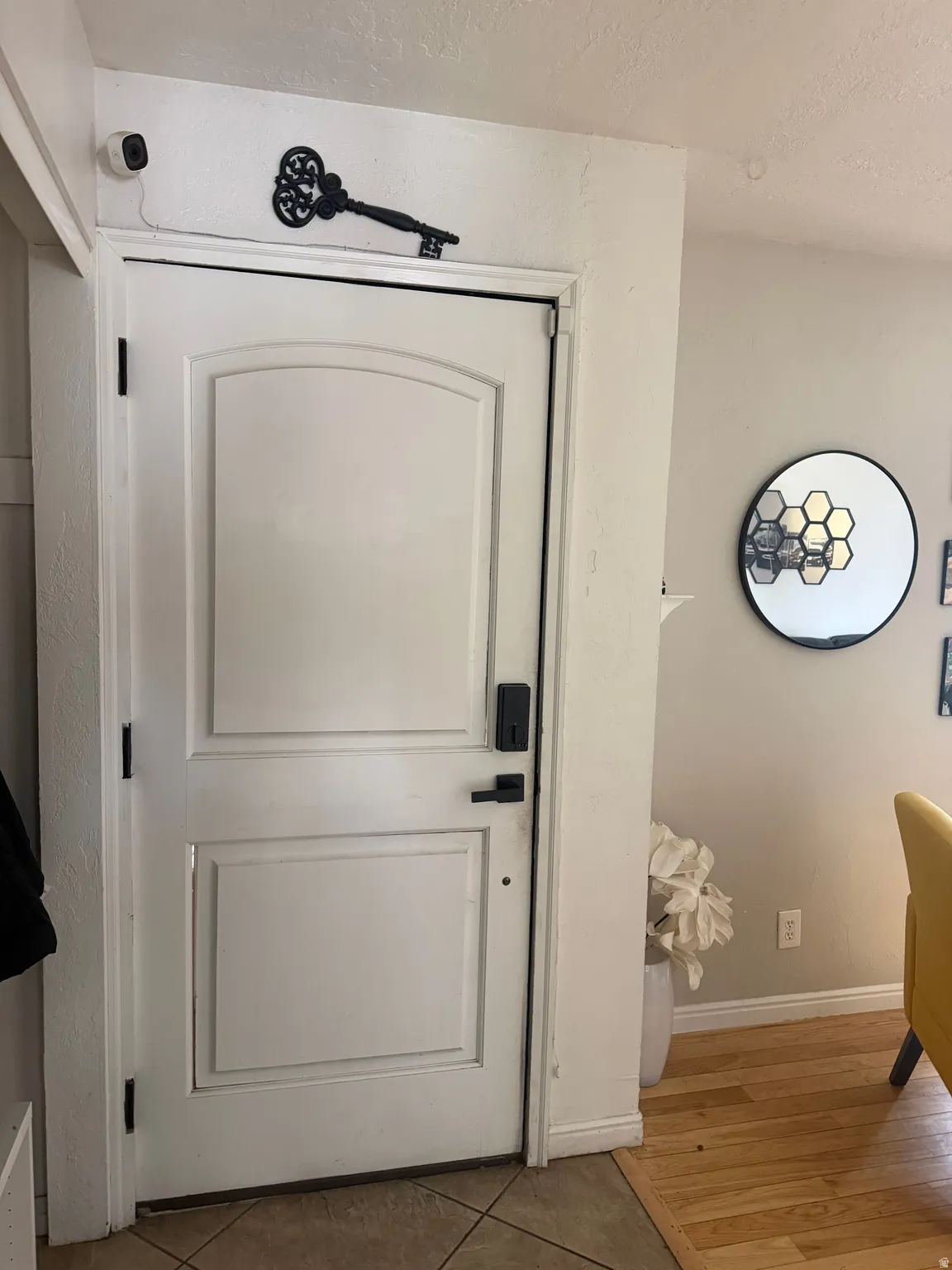 White interior door with smart lock hardware, tile flooring, and wood-finish flooring