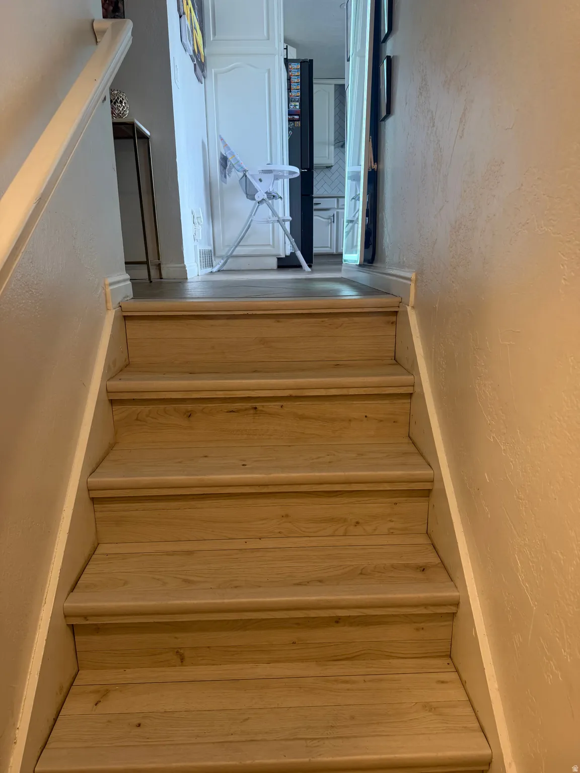 Wood-finish stair treads with white risers and a matching handrail