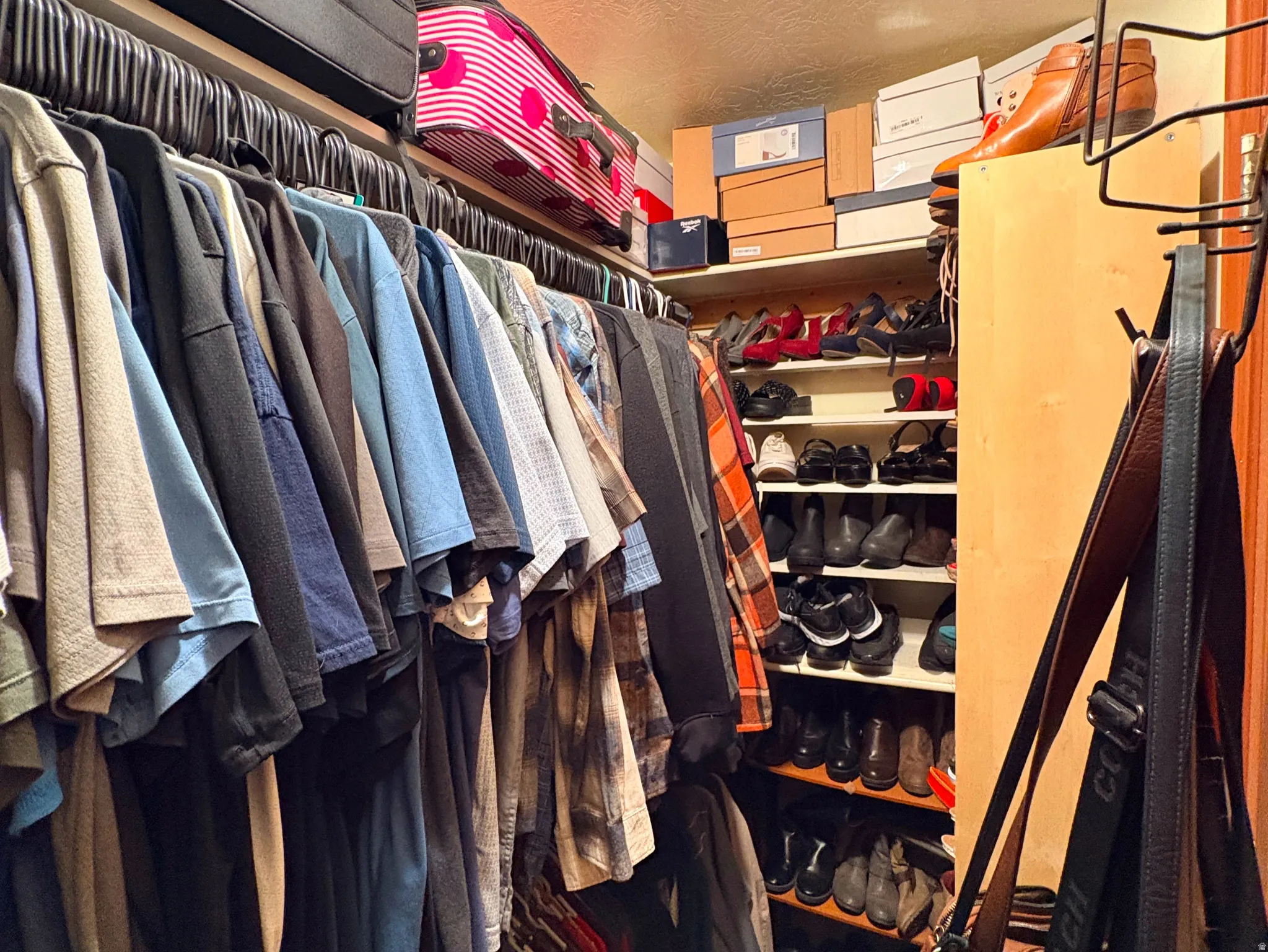 Built-in closet organization system featuring multiple hanging rods, corner shelving, and upper storage ledges