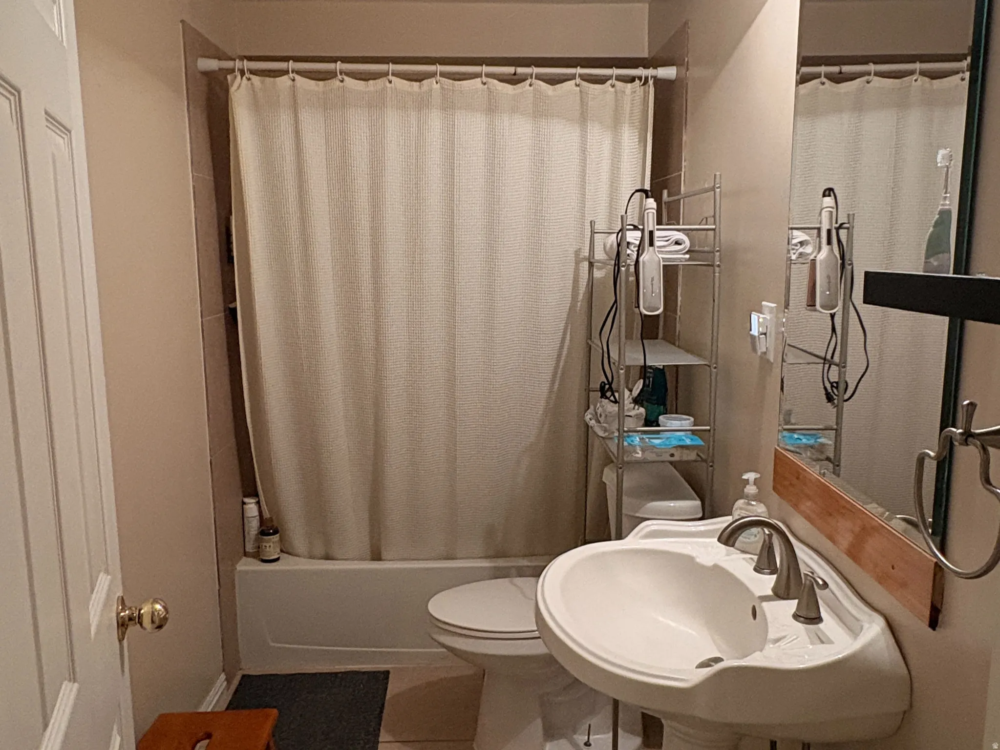 Pedestal sink with dual-handle faucet, white bathtub, and tile flooring