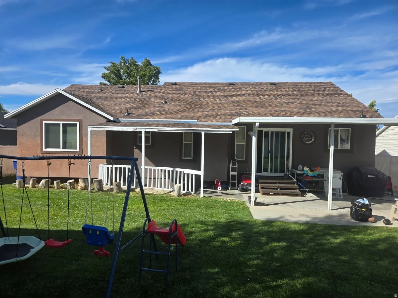 Expansive backyard featuring a manicured lawn, concrete patio, and covered porch with a ramp