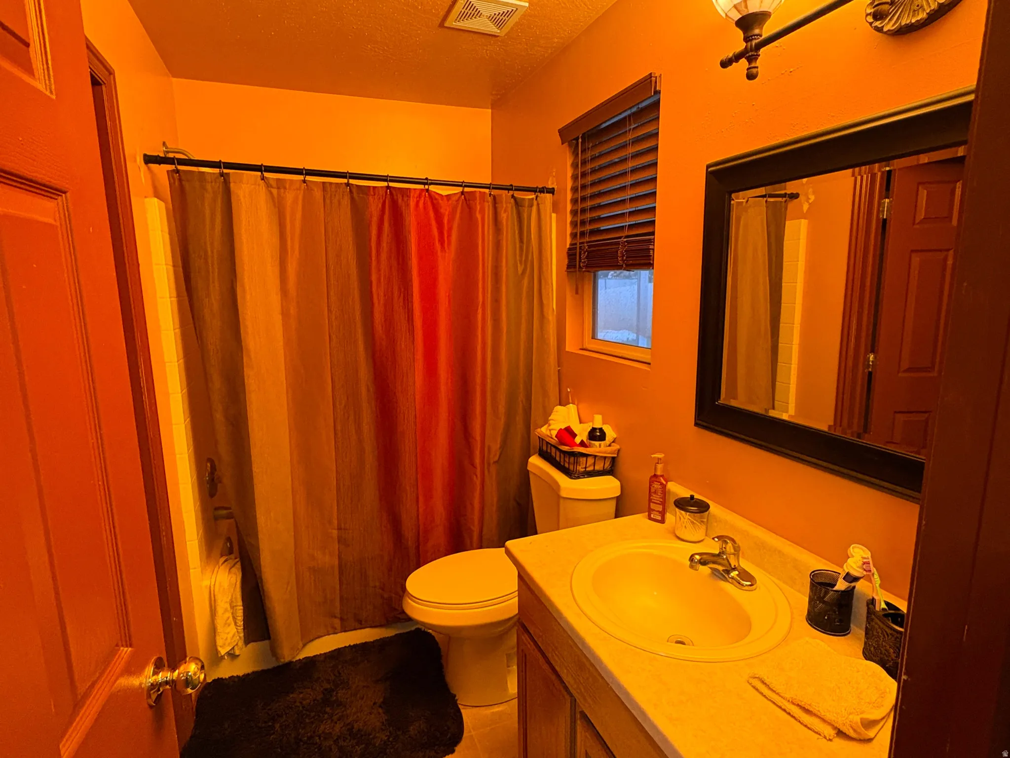 Vanity with integrated sink, wood cabinetry, and a framed wall mirror