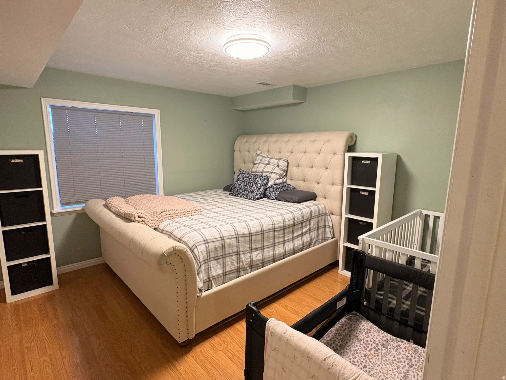 Wood-finish flooring throughout, complemented by a light green wall finish