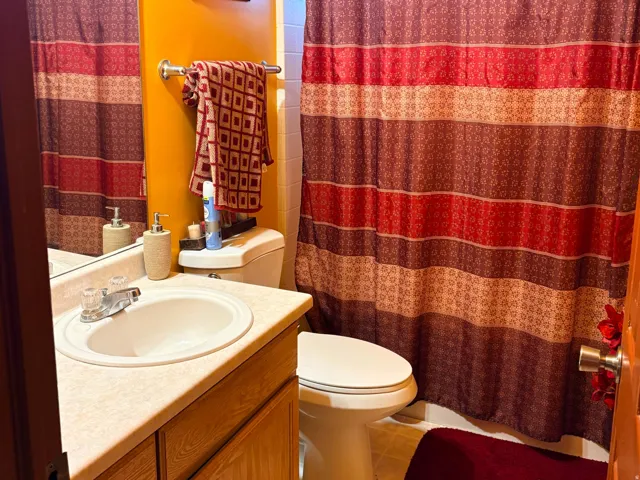 Vanity with an integrated sink, light wood-finish cabinetry, and a wall-mounted mirror