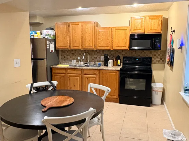 Kitchen featuring wood-finish cabinetry, stainless steel refrigerator, black range, and an integrated microwave