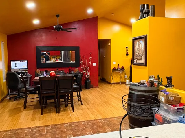 Vaulted ceiling, recessed lighting, wood-finish flooring, ceiling fan, and wall-mounted mirror